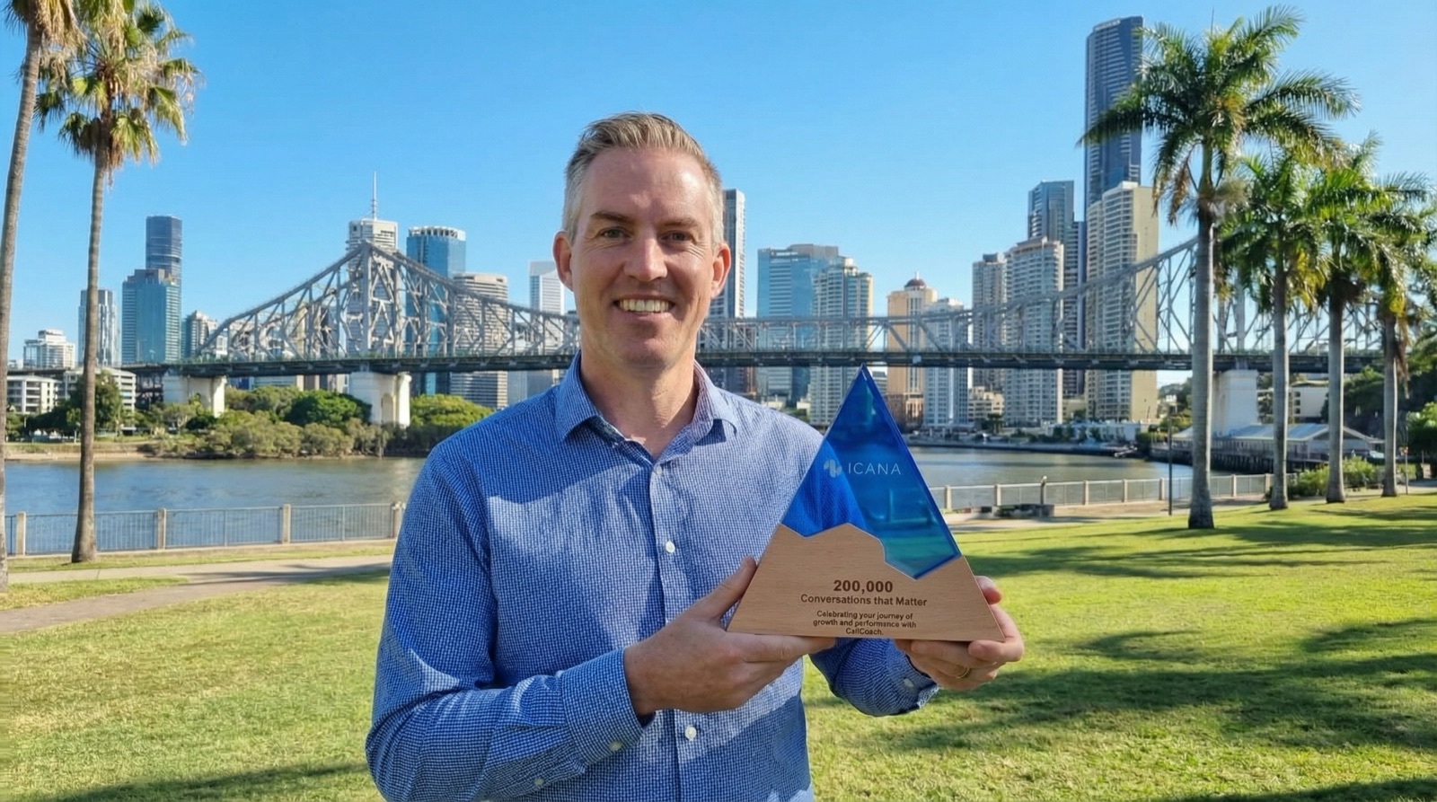 Chris Doyle, Chief Information Officer at Finance One, holding the Icana.AI 200,000 Conversations that Matter award beside the Brisbane River