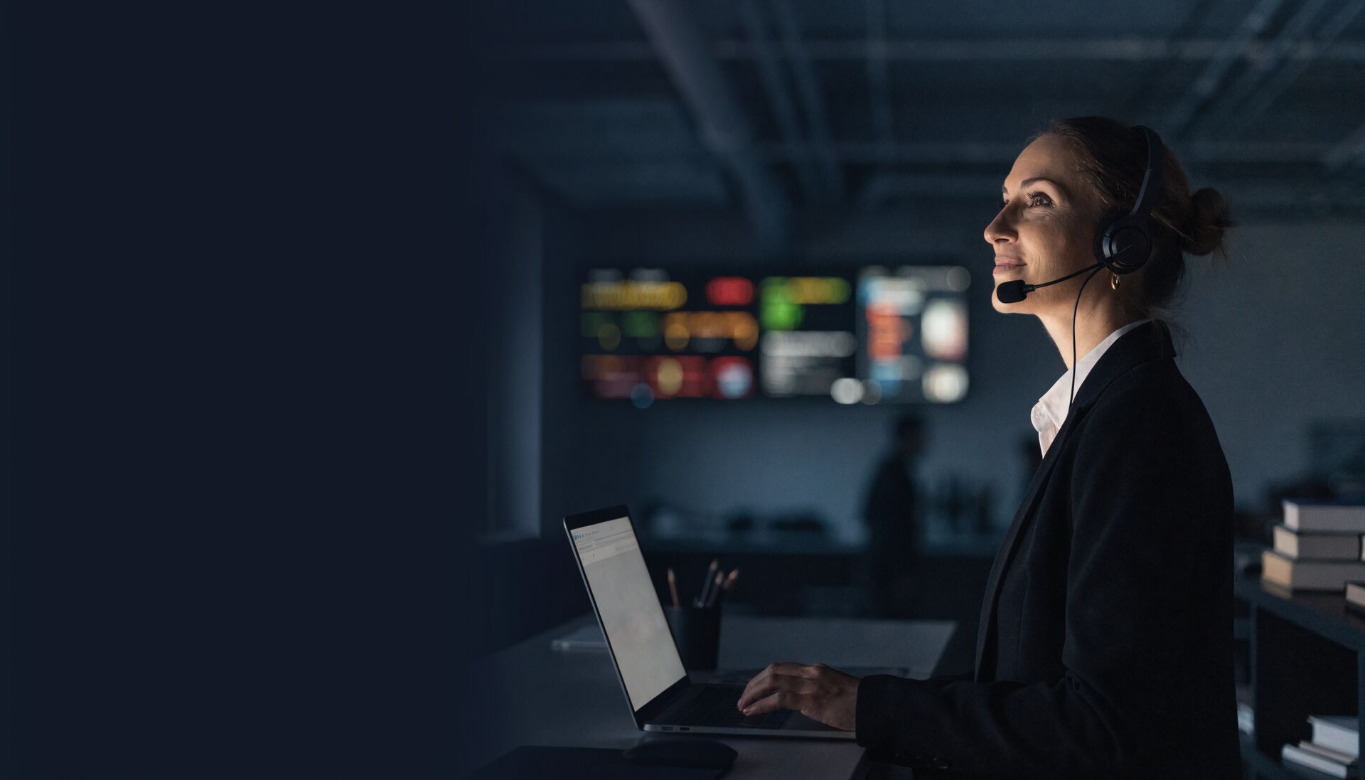 A call centre coach with a headset reviewing performance on a laptop