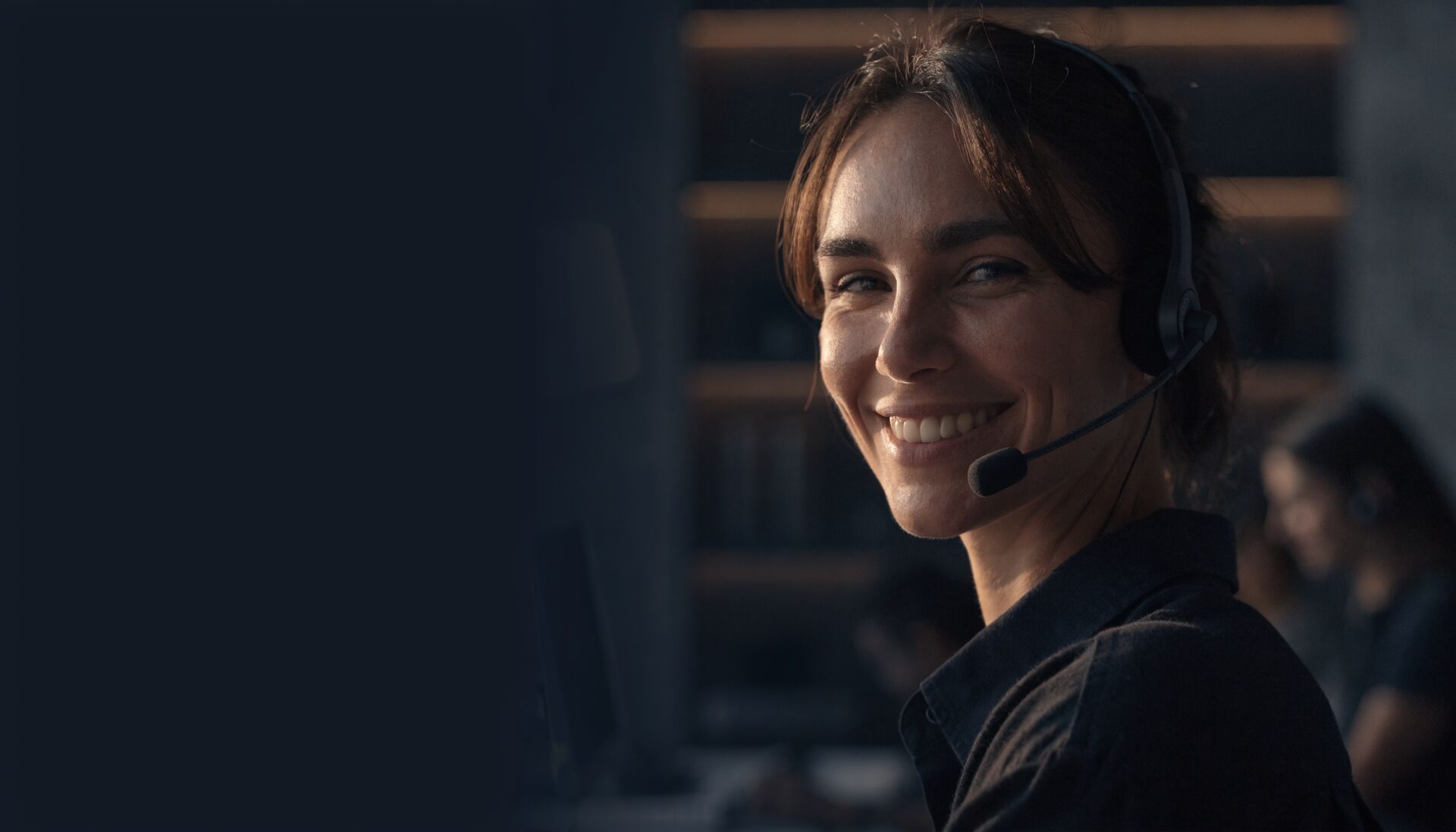 A contact centre agent with a headset smiling during a customer call