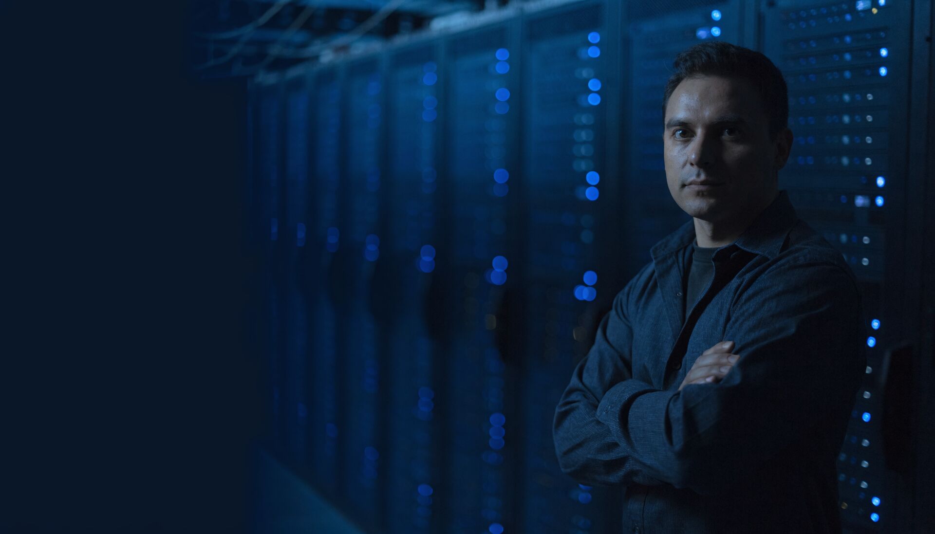 An engineer standing in a dim data centre aisle